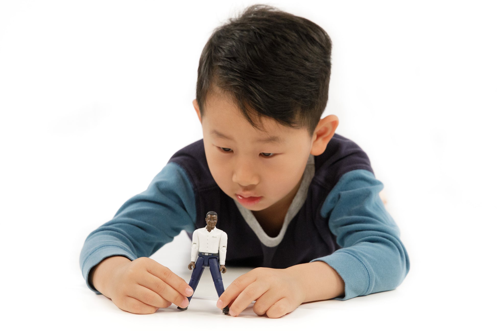 Young boy engaging with a dark-skinned articulated figure wearing a white shirt and dark blue jeans for imaginative play