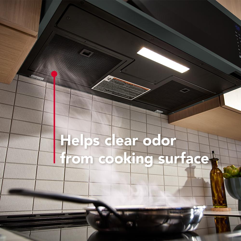 Under-cabinet microwave hood with dual fans ventilating steam from stovetop in a modern kitchen setting