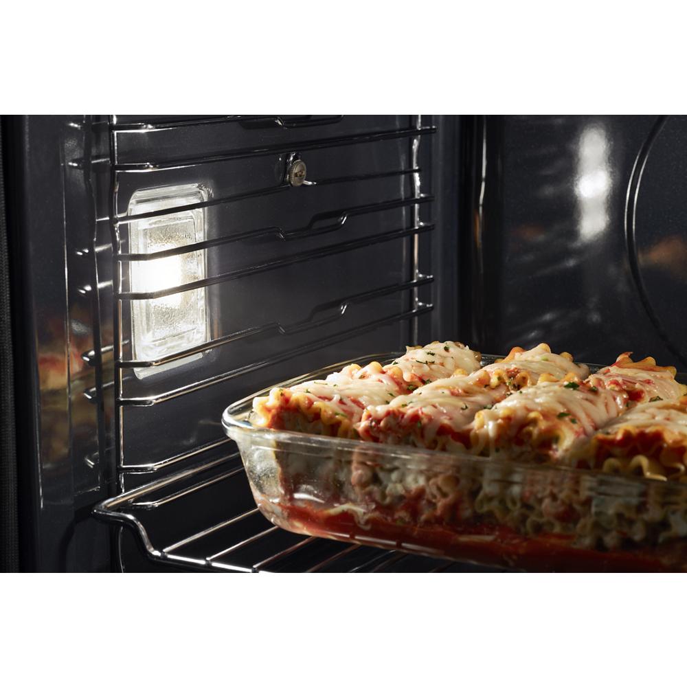 Glass baking dish with cheesy lasagna cooking inside a stainless steel wall oven from kitchen appliances collection