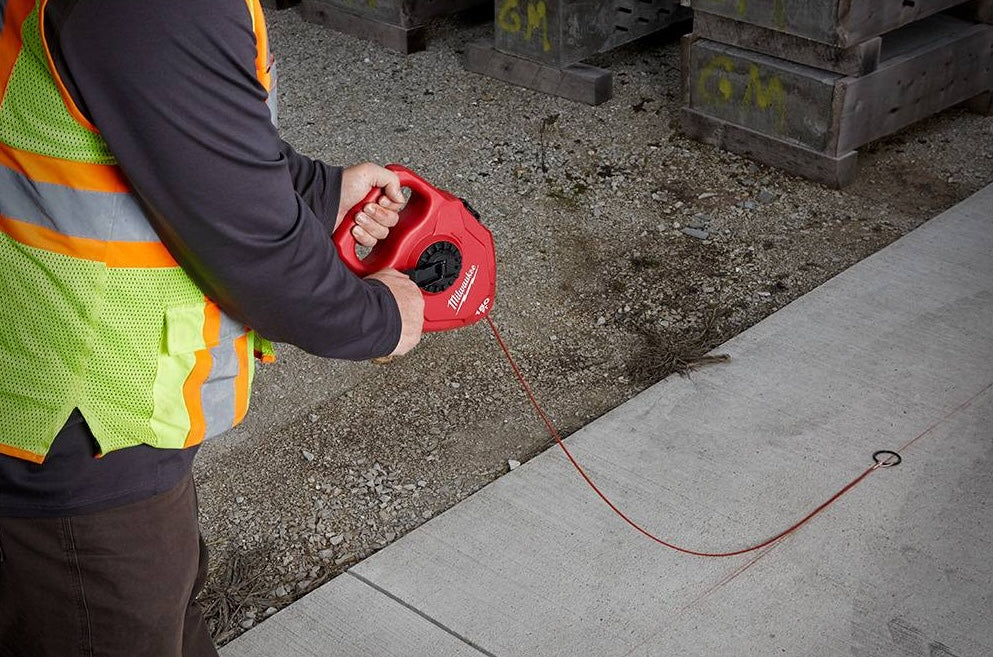 Person using red Milwaukee chalk reel with large capacity for marking concrete in construction and woodworking tools collections