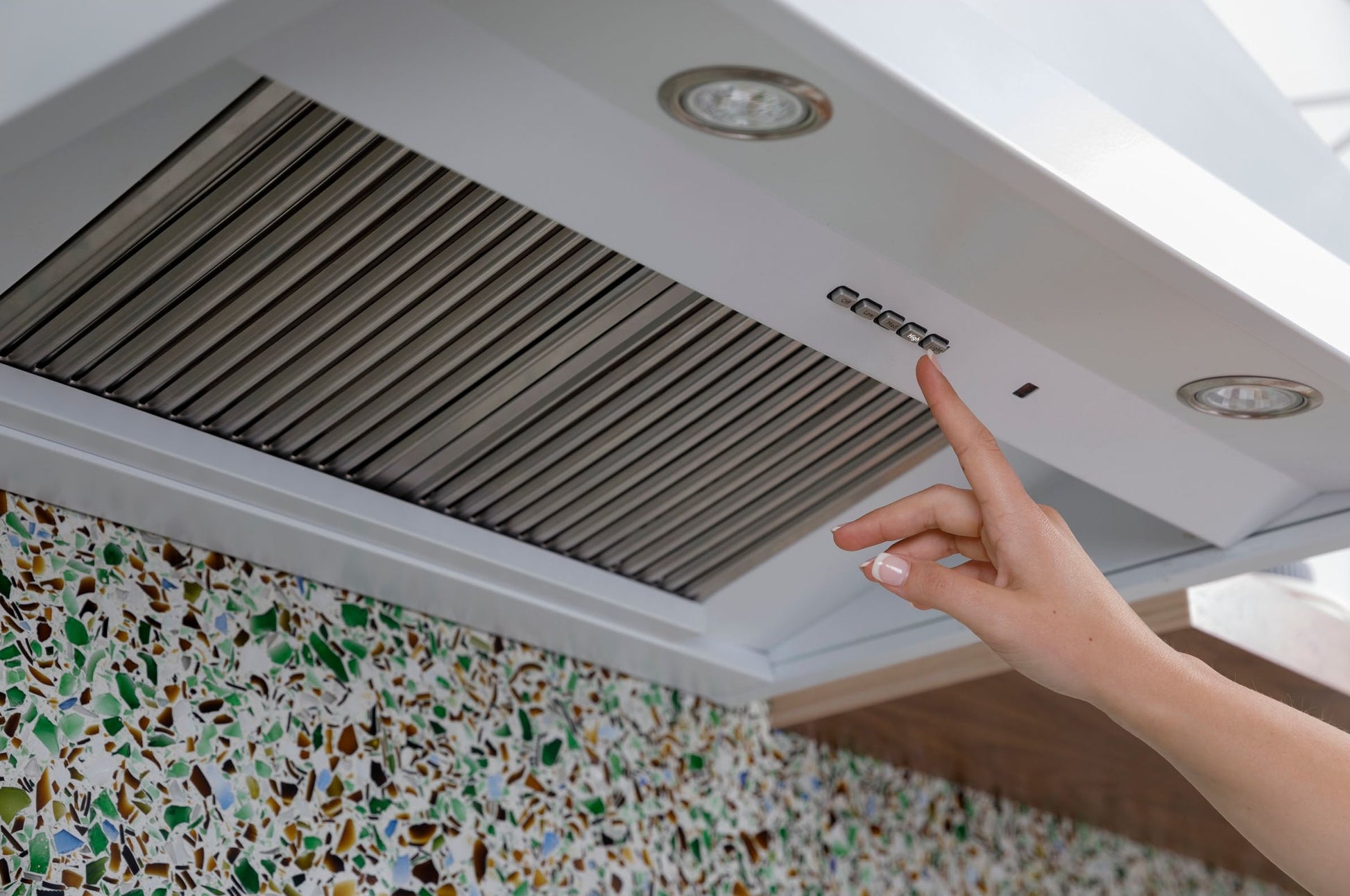 White commercial range hood with push-button controls and built-in lighting in modern kitchen setting
