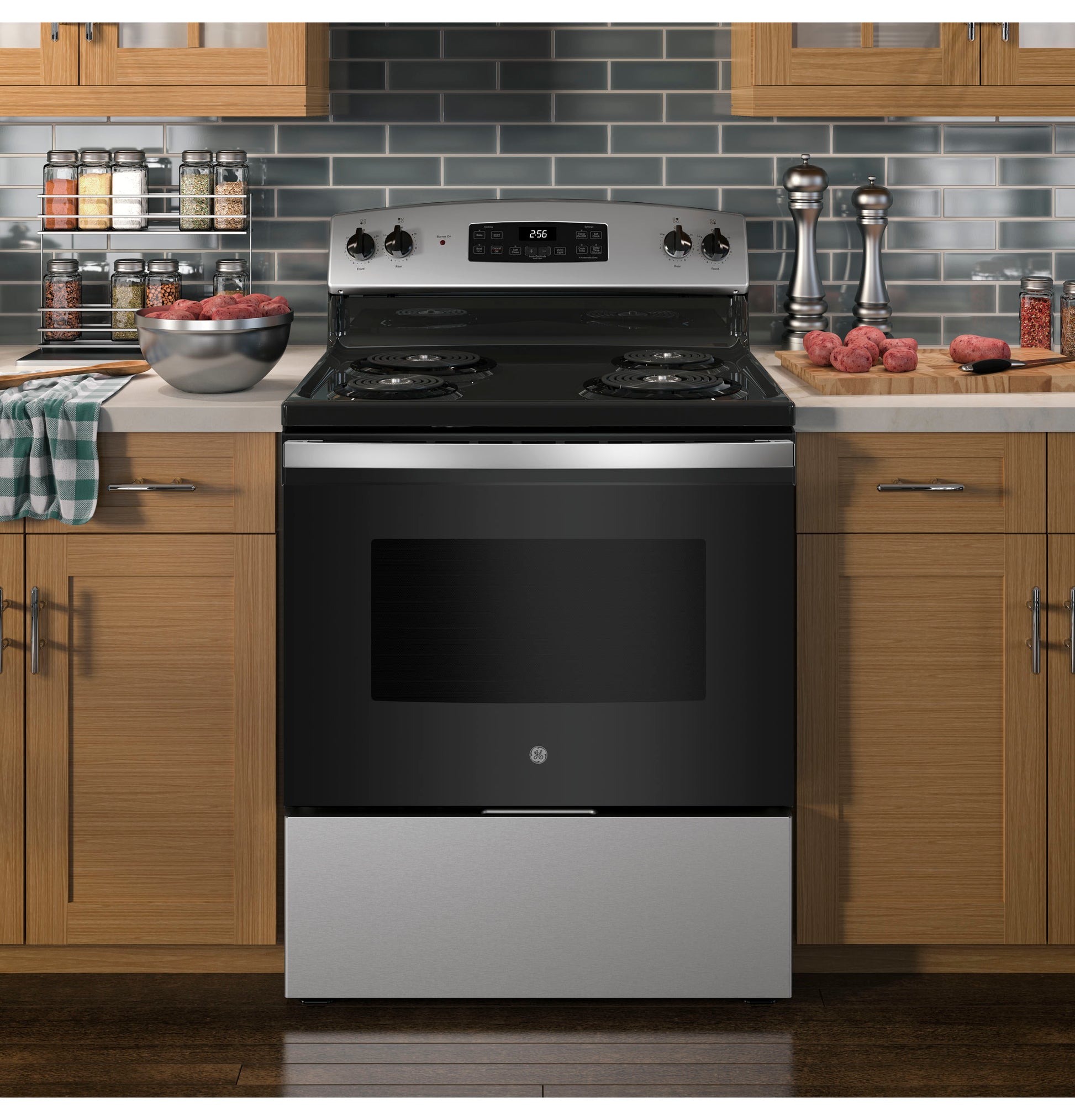 Stainless steel and black electric range with coil burners in modern kitchen featuring wood cabinets and tiled backsplash