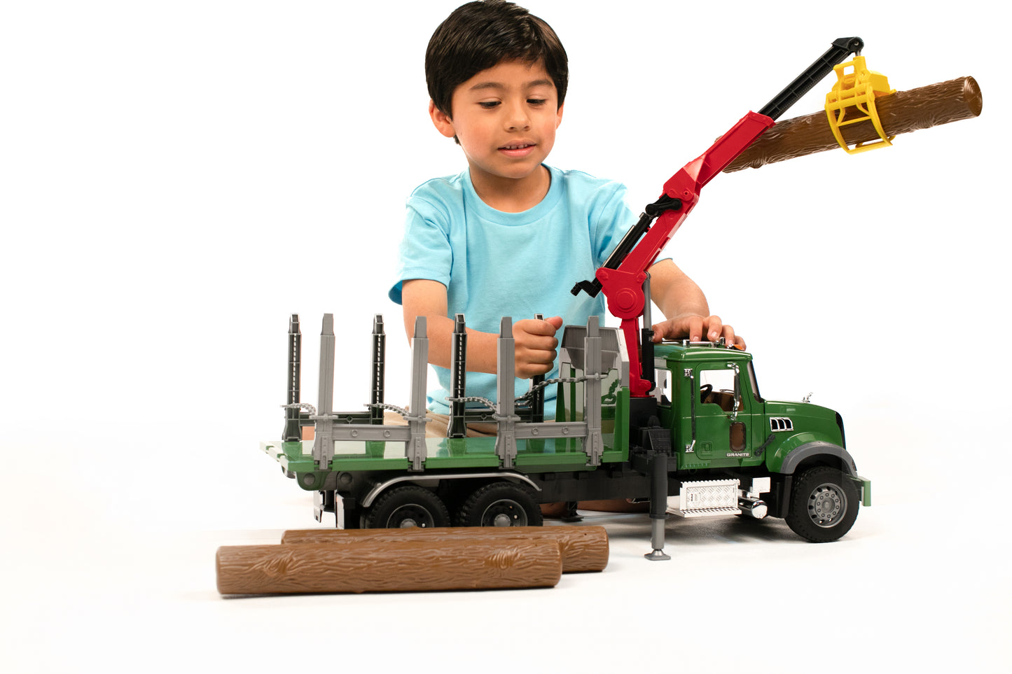 Child plays with green MACK timber truck toy featuring red loading crane lifting log in Toys & Games collection