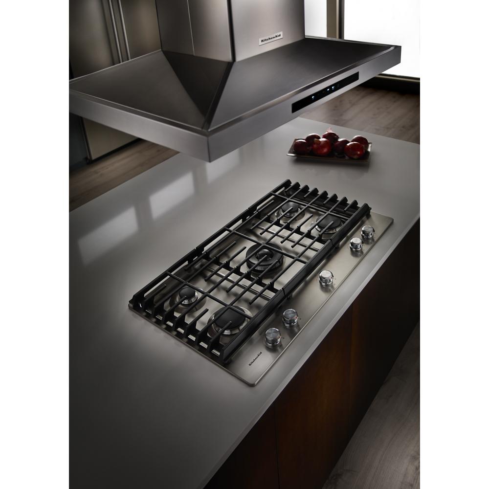 Stainless steel island-mount canopy hood with digital controls above a gas cooktop in modern kitchenware and appliances setting