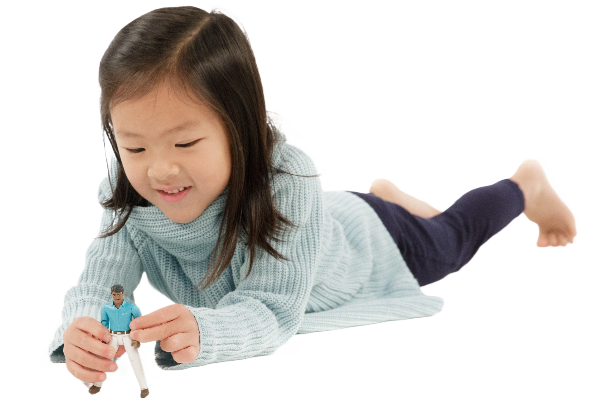Young girl wearing light blue sweater and dark pants playing with action figure in teal shirt and white jeans