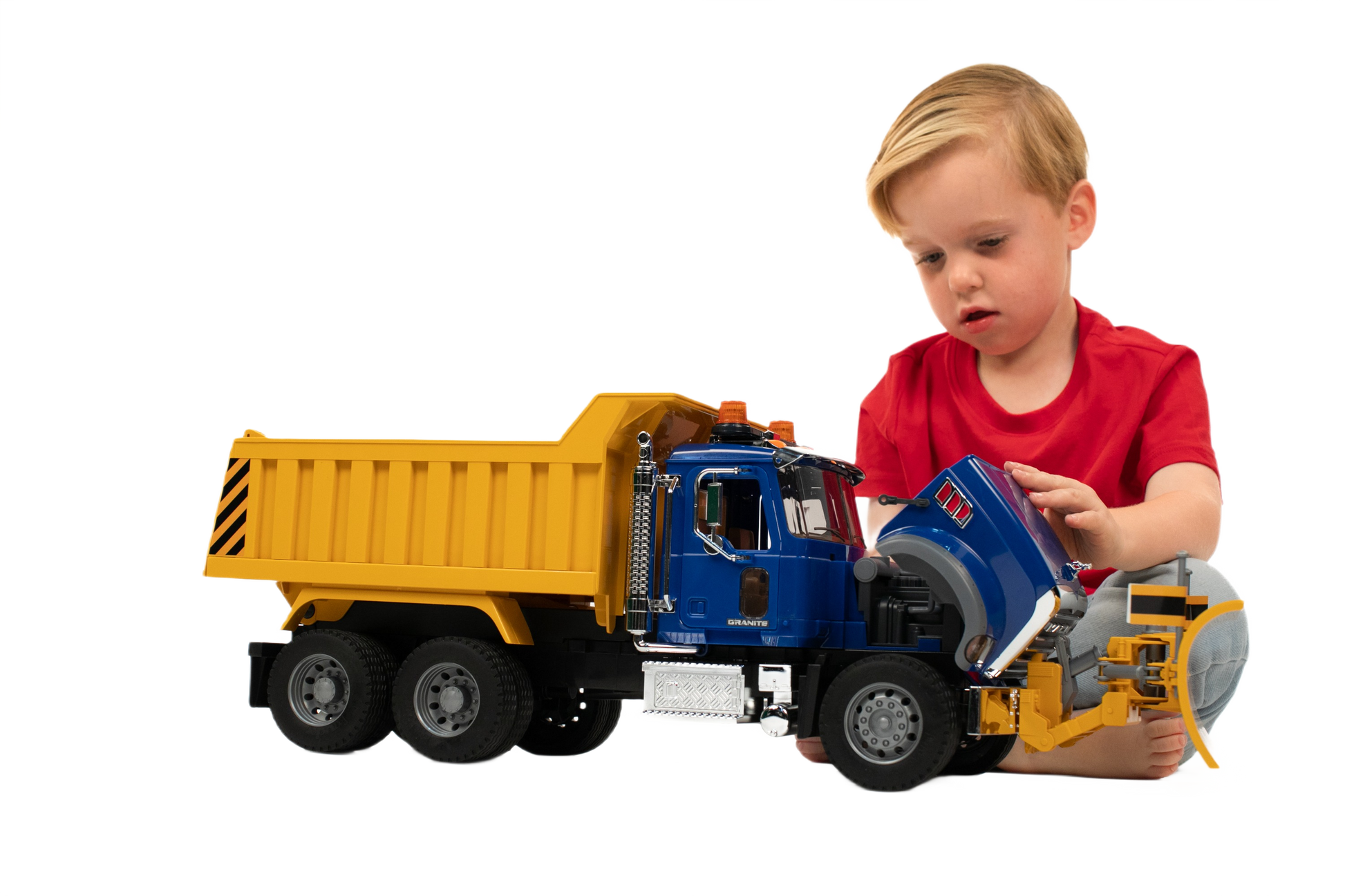 Young child playing with blue and yellow Mack Granite dump truck toy with front plow for tools and home improvement play