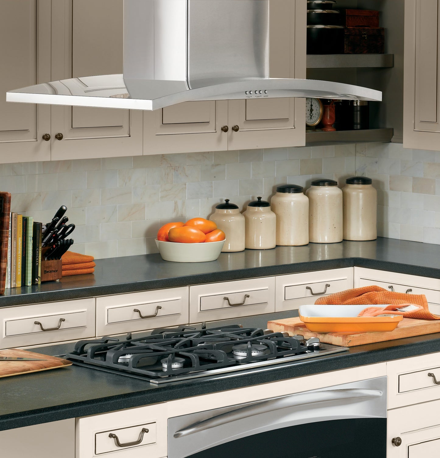 Modern kitchen scene with stainless steel island hood above gas cooktop and light-toned cabinetry in home improvement setting