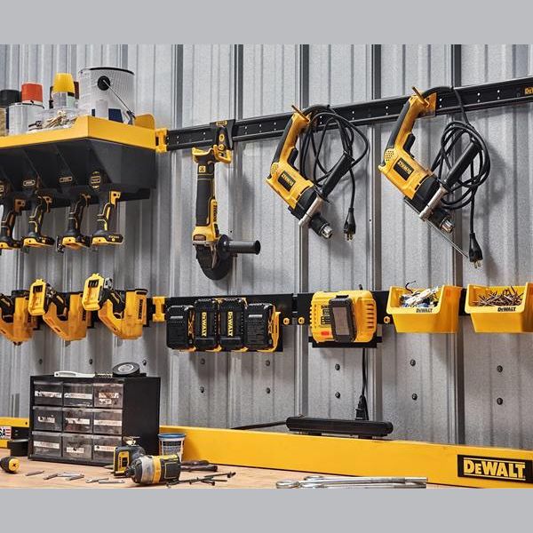 Wall-mounted yellow and black metal rails with power tools, chargers, and storage bins for workshop tool organization