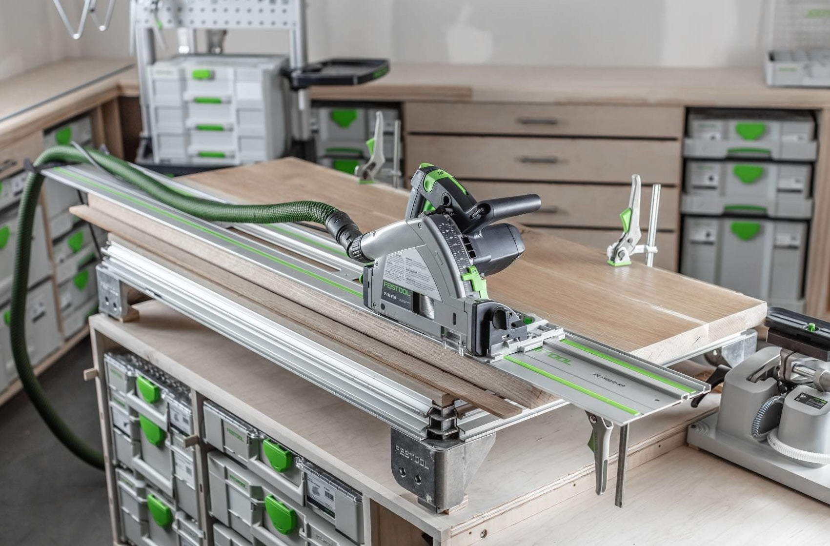 Plunge-cut track saw with 55" guide rail on workbench surrounded by organized storage boxes in workshop