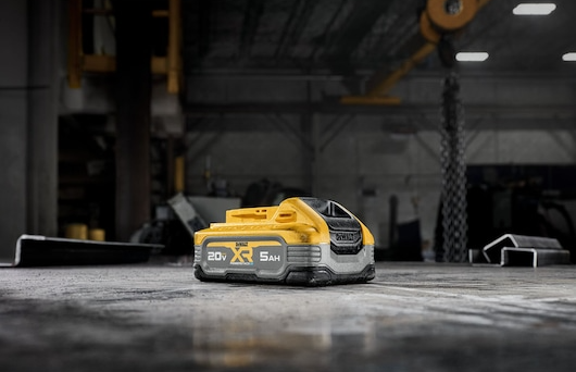 Yellow and gray DEWALT 20V 5Ah XR POWERSTACK battery on a workshop floor for tools and home improvement tasks