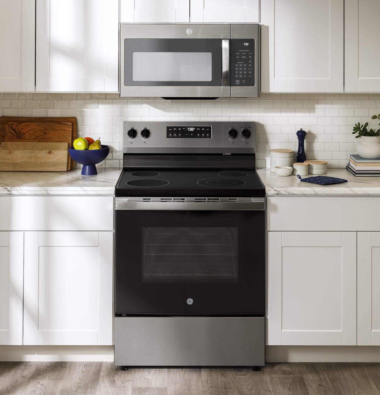 Modern stainless steel electric range with smooth cooktop and digital control panel in white kitchen setting