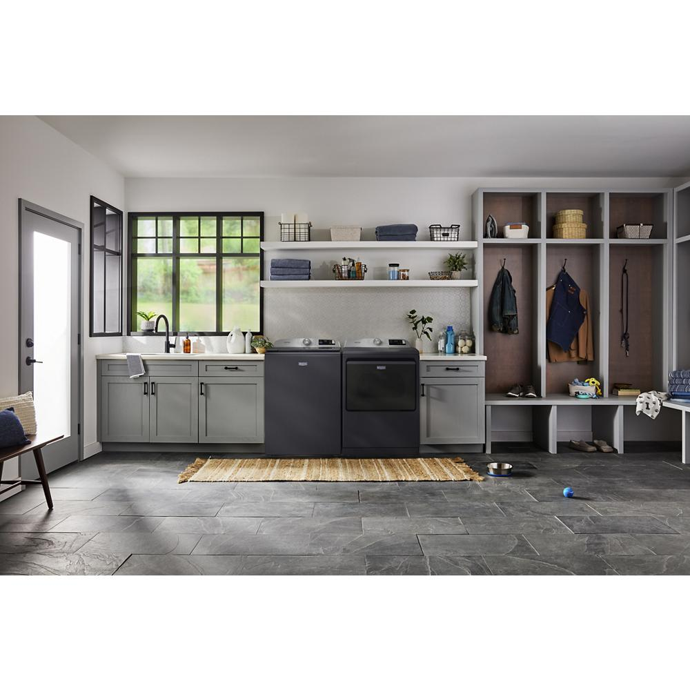 Laundry room with matte black top load washer and dryer, gray cabinets, open shelves, and bench with storage cubbies