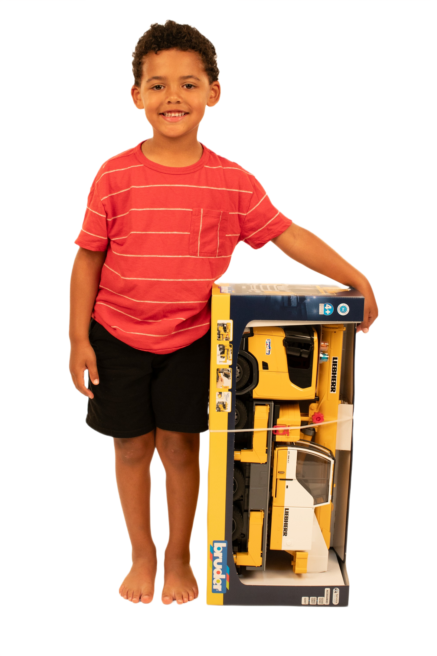 Young boy standing barefoot with Bruder yellow Liebherr crane truck toy in original packaging in Toys & Games collection
