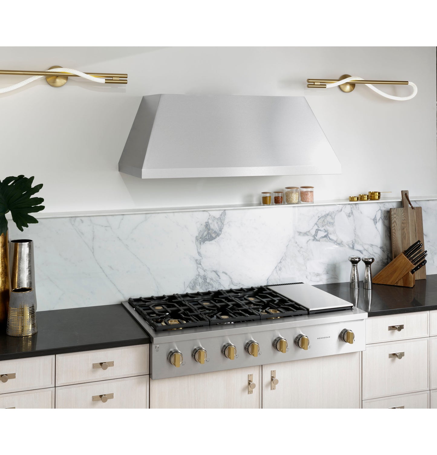 Stainless steel professional gas rangetop with six burners and griddle set in modern kitchen with marble backsplash