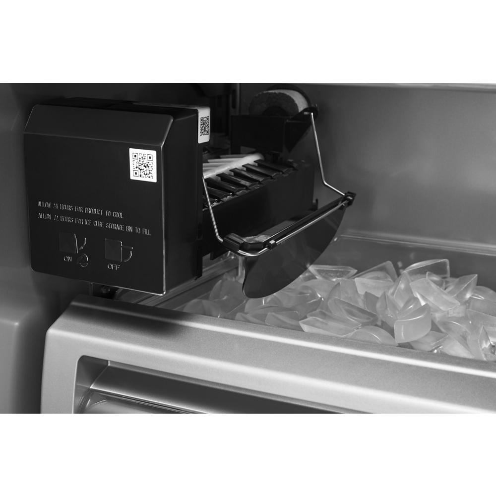 Close-up of ice maker dispensing cubed ice inside built-in KitchenAid side-by-side refrigerator interior