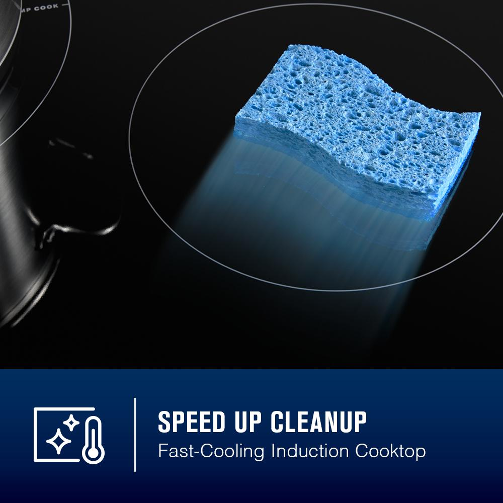 Blue cleaning sponge resting on black induction cooktop surface with pot and kitchen appliance setting visible