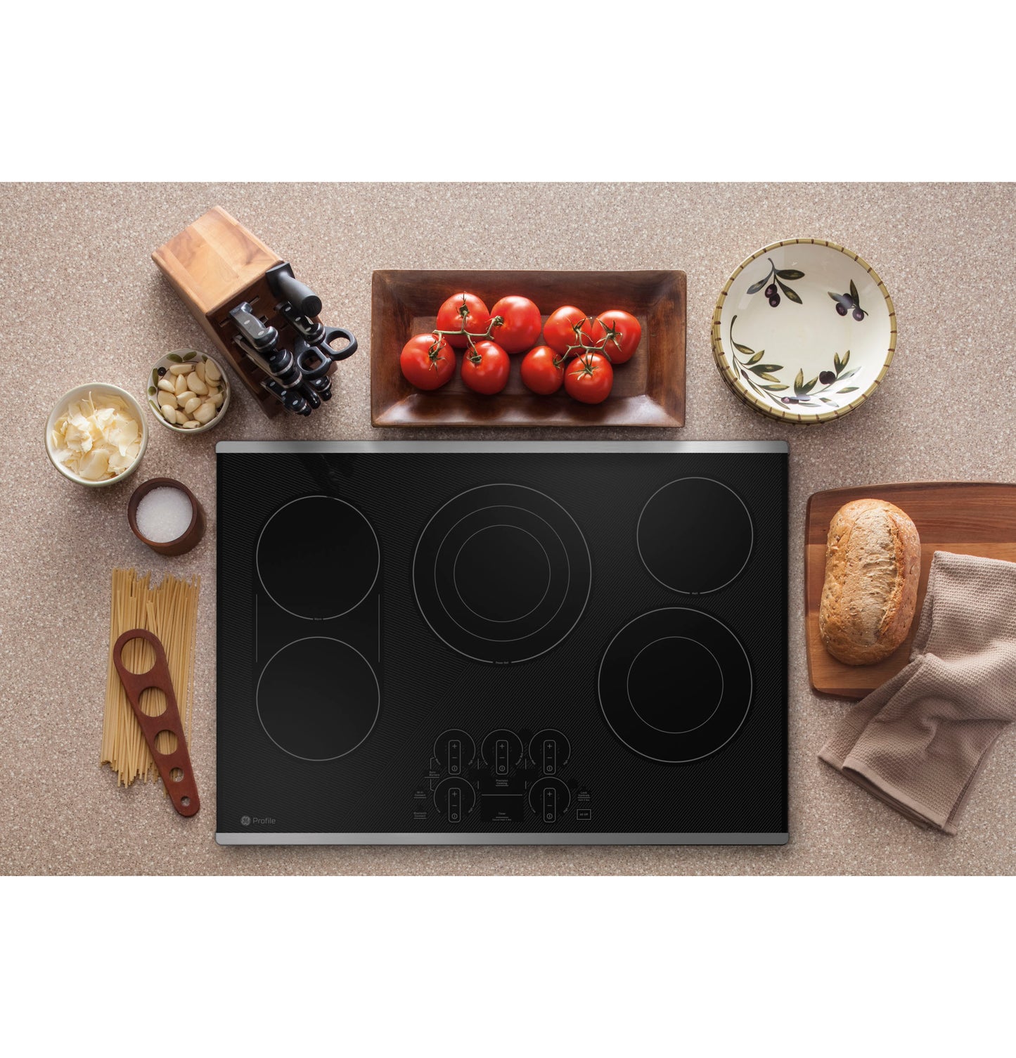 Black built-in electric cooktop with touch controls surrounded by cooking ingredients in kitchen setting