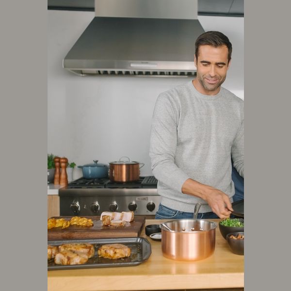 Man cooking in modern kitchen with stainless steel pyramid chimney wall hood from Wall Mounted Range Hoods collection