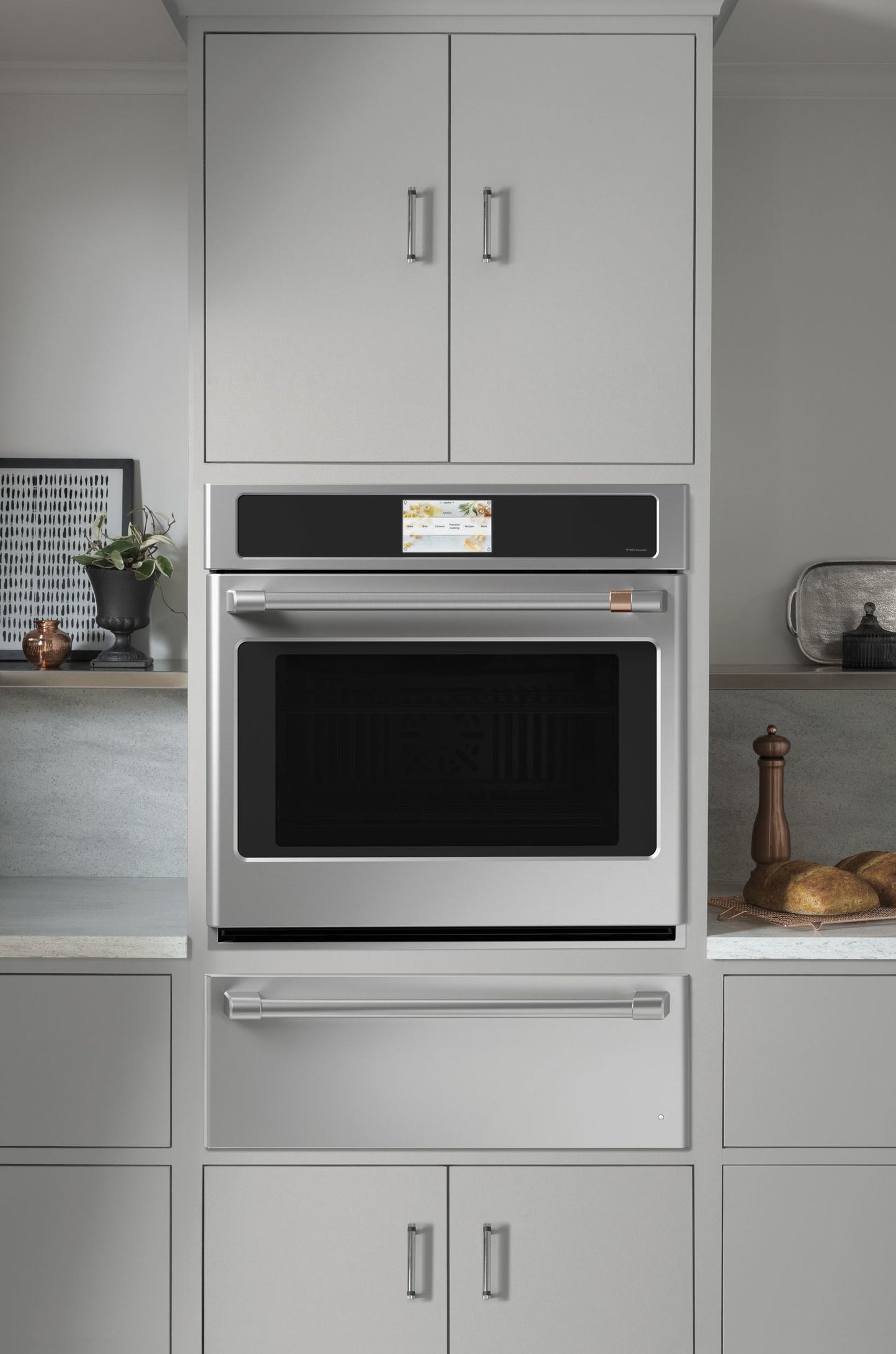 Modern built-in stainless steel wall oven with warming drawer integrated in light gray cabinetry from kitchen appliances collection