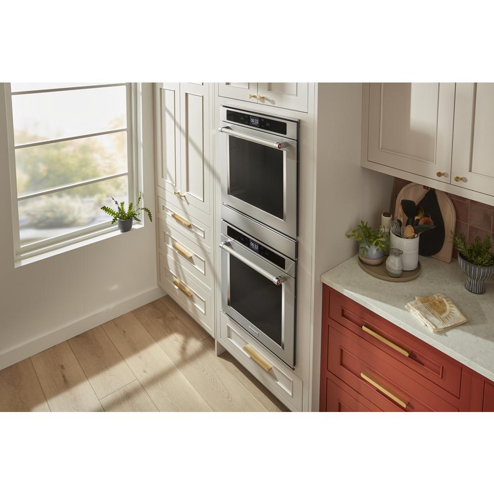 Built-in double wall ovens with stainless steel trim installed in a modern kitchen setting with cabinetry and natural light.