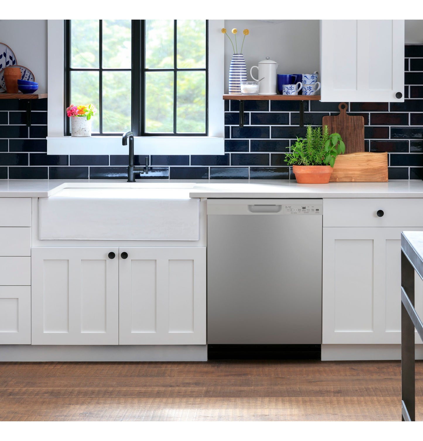 Modern kitchen with stainless steel dishwasher built into white cabinetry and black subway tile backsplash