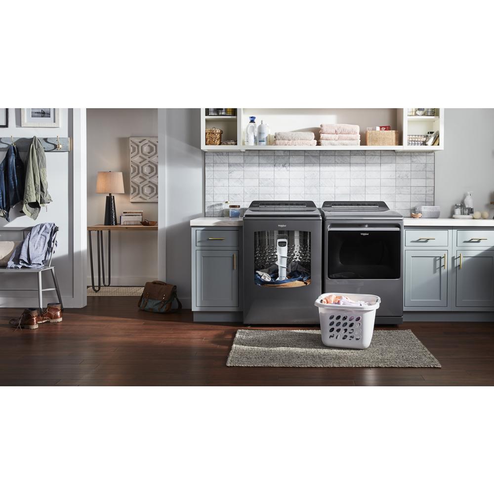 Modern dark gray top load gas dryer with open door next to matching washer in stylish laundry room setting