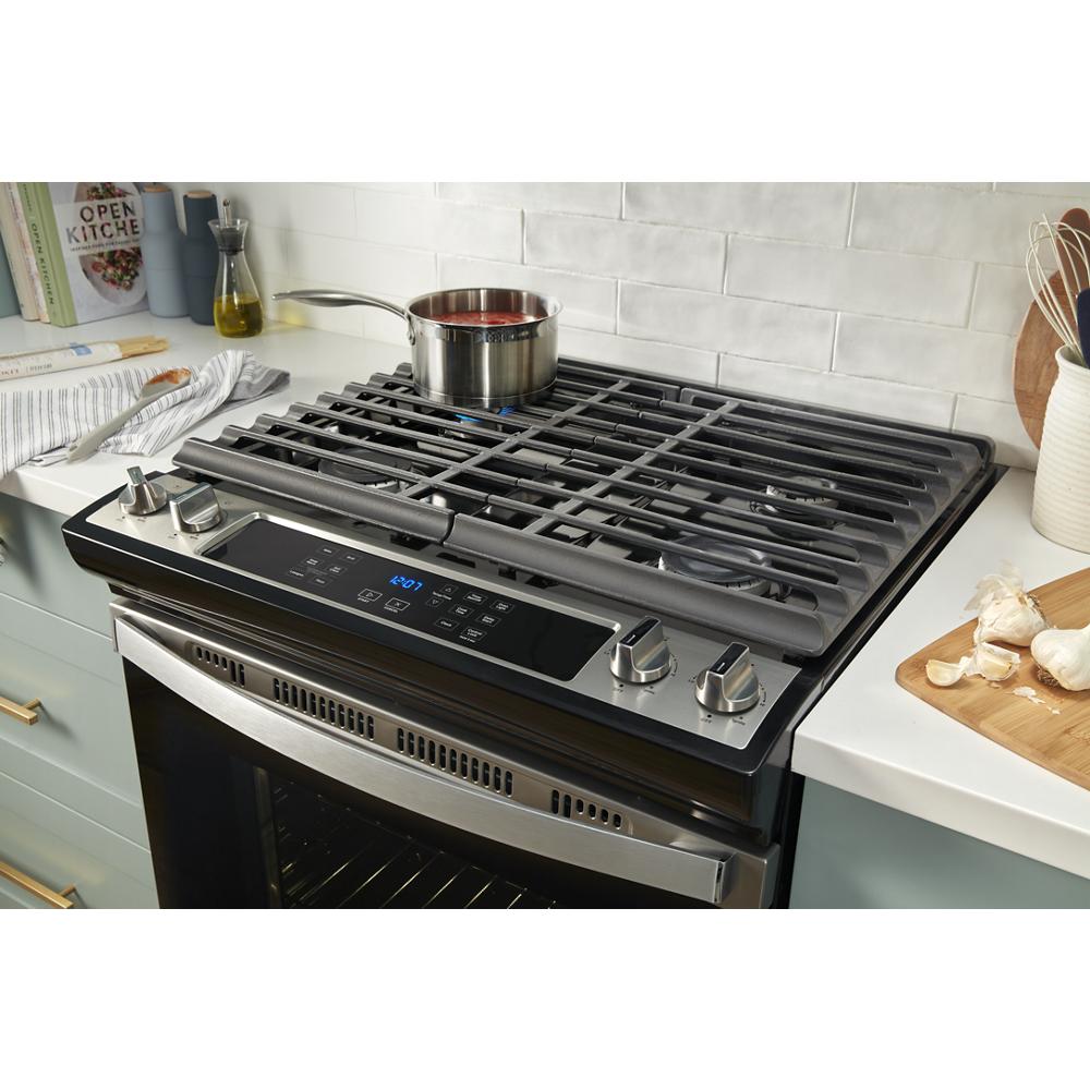 Stainless steel gas range cooktop with edge-to-edge cast iron grates, digital controls, and a pot simmering from Ranges collection