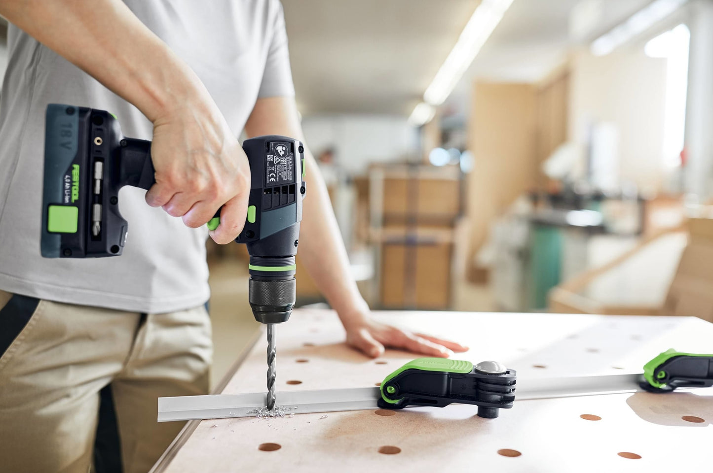 Person using a cordless drill to make precise holes in wood on a workbench in a woodworking power tools setting