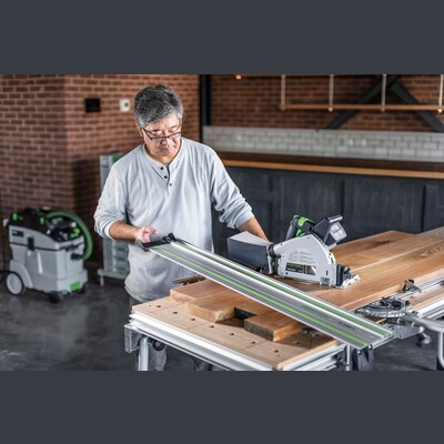 Person setting up Festool cordless track saw with guide rail on workbench for home improvement and power tools