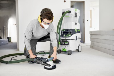 Person using Festool diamond grinder with dust extraction on floor surface during home improvement project