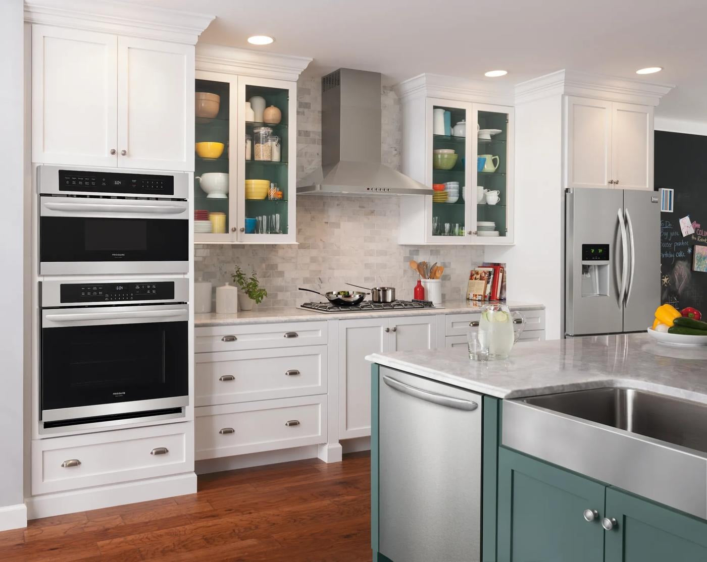 Modern kitchen with a 36" stainless canopy wall-mount hood above a gas cooktop, surrounded by white cabinetry and glass-front cabinets, part of Wall Mounted Range Hoods, Range Hoods, Kitchen & Kitchenware, and Appliances collections.