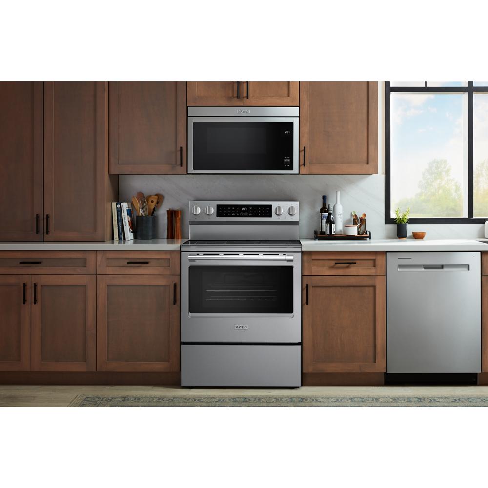 Stainless steel electric range with microwave above, surrounded by wooden cabinetry in a modern kitchen setting