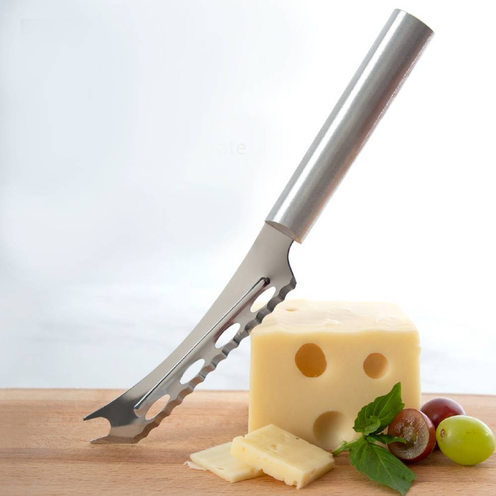 Stainless steel serrated cheese knife with forked tip resting on wooden board with Swiss cheese and grapes in kitchenware collection