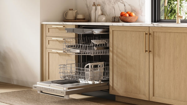 Open stainless steel anti-fingerprint dishwasher extended with empty racks in modern kitchen featuring wood cabinetry and marble countertop