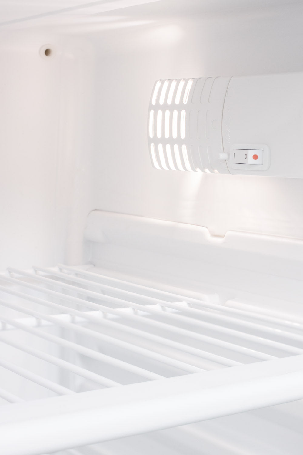 Interior view of white refrigerator with wire shelf and illuminated vent control panel for temperature regulation