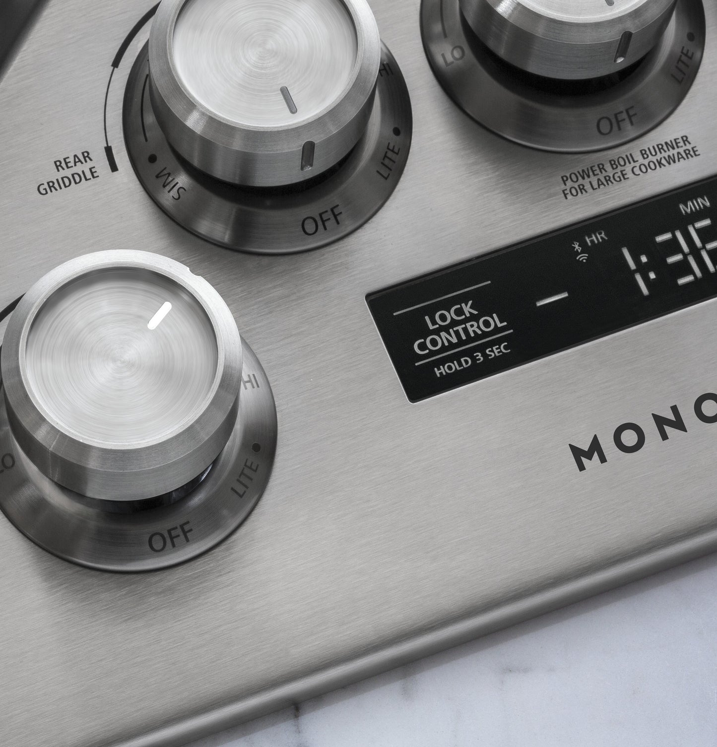 Close-up of brushed stainless steel control knobs and digital lock timer on Monogram gas cooktop in Kitchen & Kitchenware collections