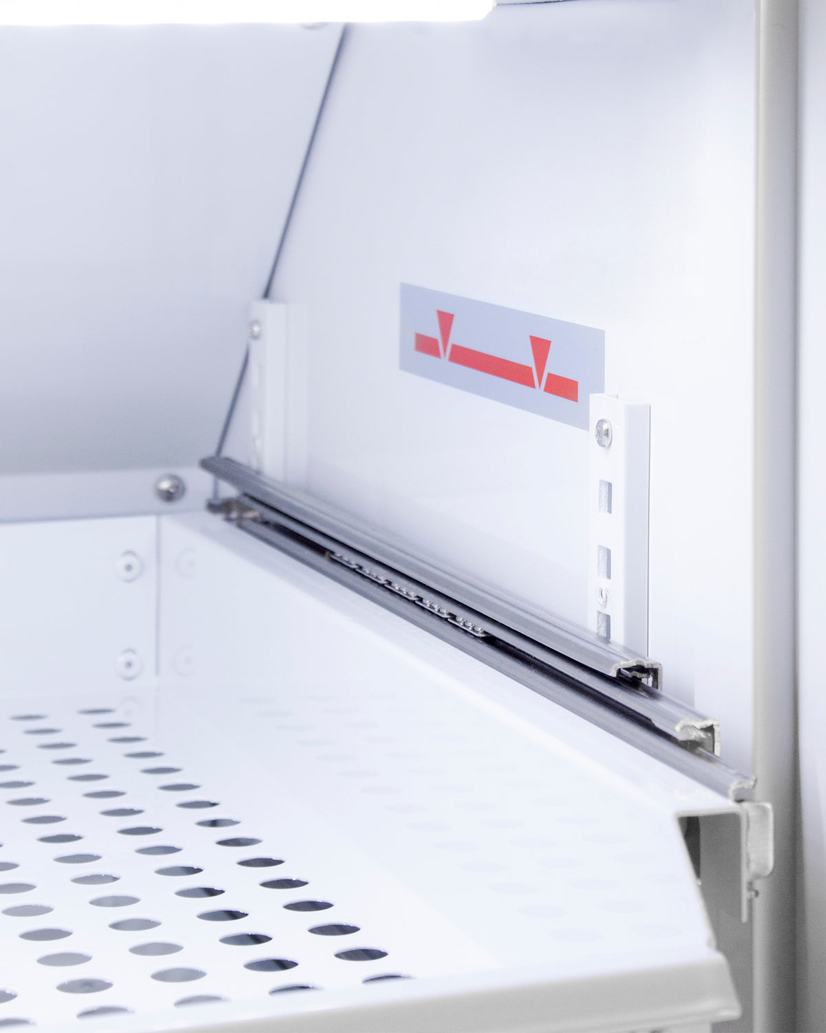 Close-up of adjustable removable drawer track with perforated white metal shelf inside upright vaccine refrigerator