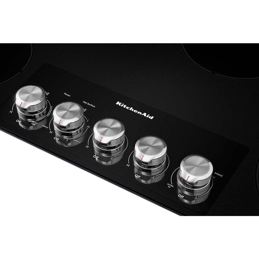 Close-up of knob controls on black electric cooktop for KitchenAid cooktops and kitchenware collections