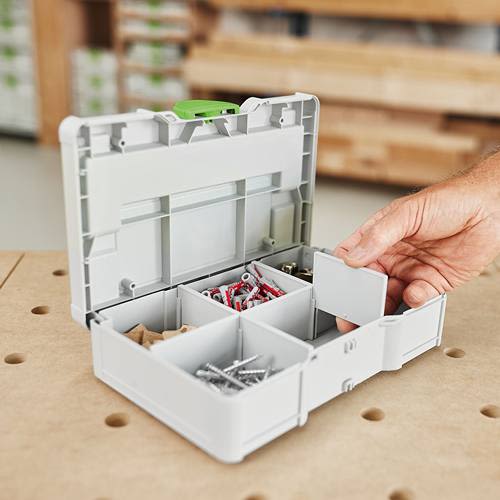 Compact white storage box with green latch and removable dividers organizing screws and hardware in workshop setting