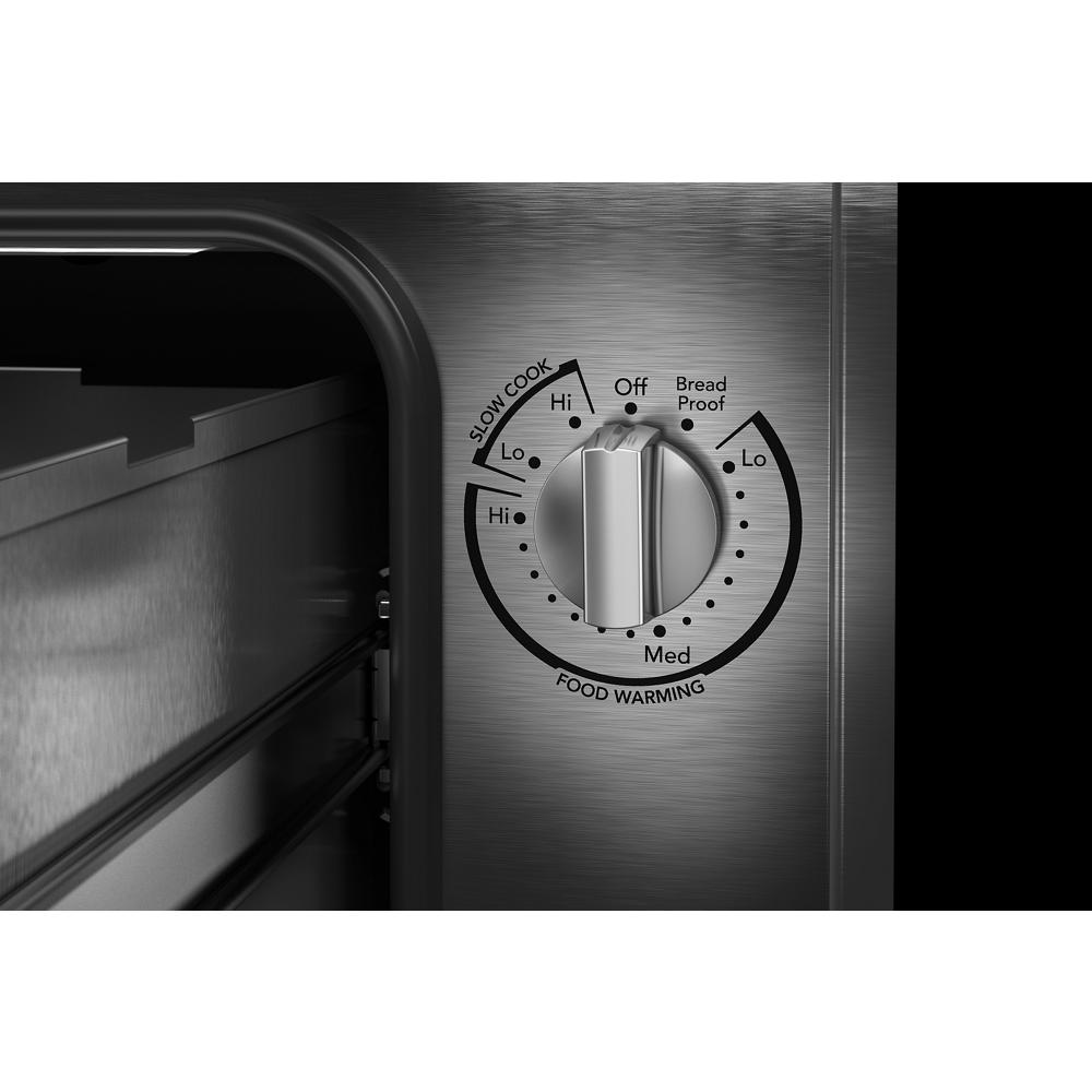 Control knob for slow cook, food warming, and bread proof settings on stainless steel warming drawer panel in KitchenAid collection.