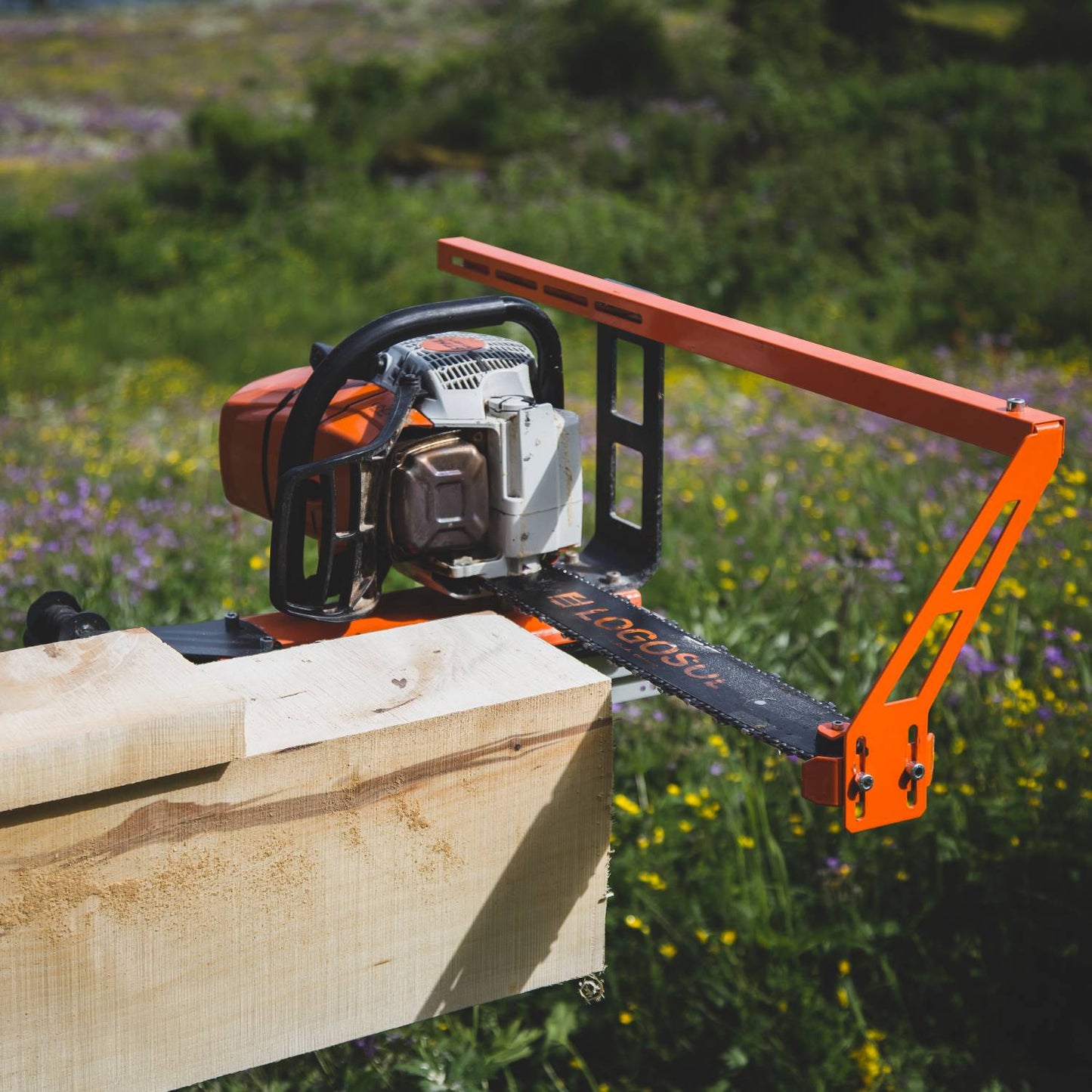 Orange bar nose top steering attachment secured to chainsaw for accurate log cutting in outdoor home improvement tasks