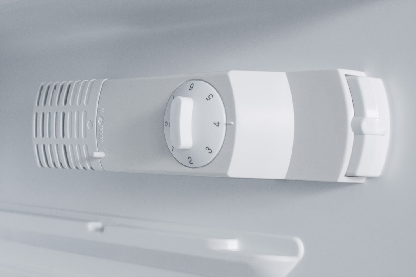 White temperature control dial with ventilation grille inside built-in refrigerator in kitchen appliance collection