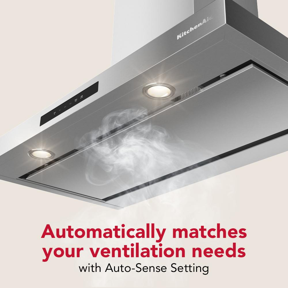 Stainless steel canopy hood with built-in lights and digital controls clearing smoke in kitchen appliance collection