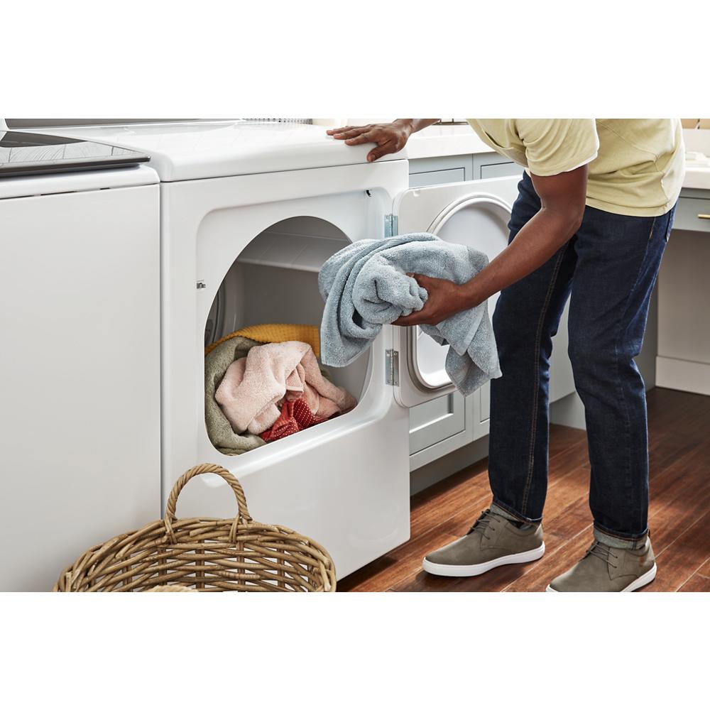 Person loading soft towels into a white long vent gas dryer in a modern laundry room setting from Dryers collection
