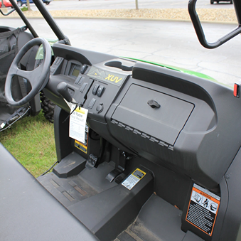 Dashboard and control panel of a mid-size John Deere utility vehicle with steering wheel and storage compartment