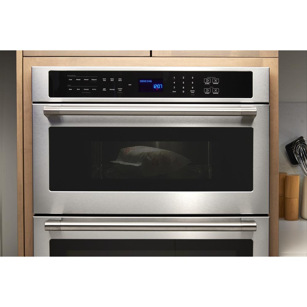 Stainless steel wall oven microwave combo with digital touchscreen control panel and glowing blue LED clock display