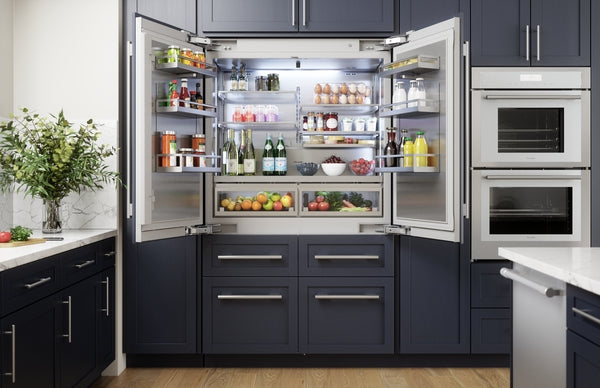 Built-in French door refrigerator with bottom freezer open to reveal organized fresh food and beverages in modern kitchen setting