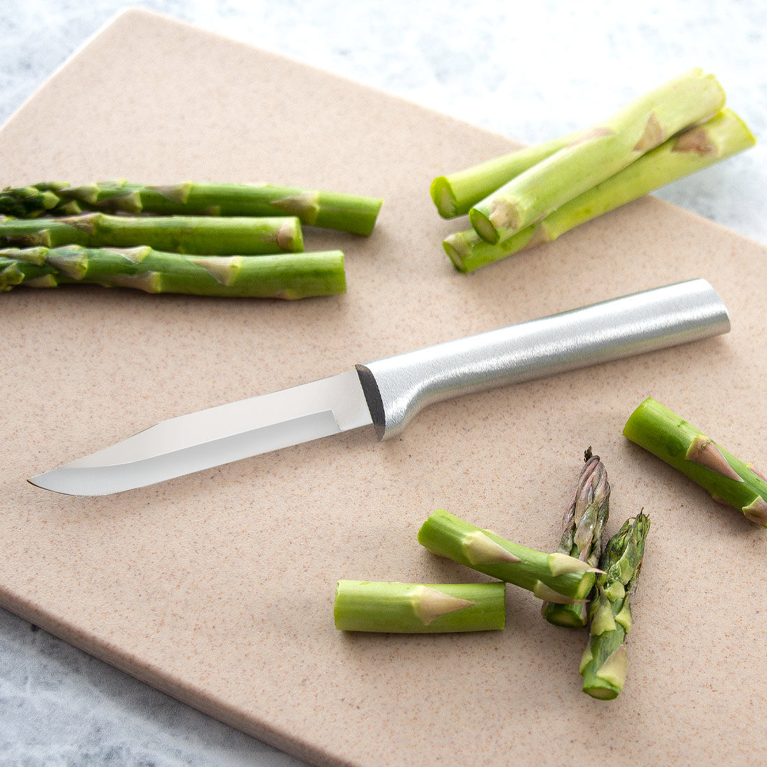 Sharp paring knife with satin-finish cast aluminum handle cutting fresh asparagus on stone cutting board in Kitchenware collections