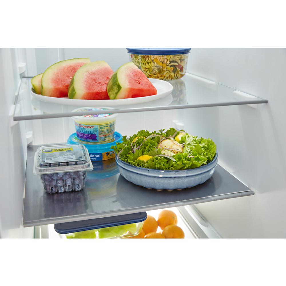 Interior view of side-by-side refrigerator with fresh fruit, salad, and storage containers on frameless glass shelves