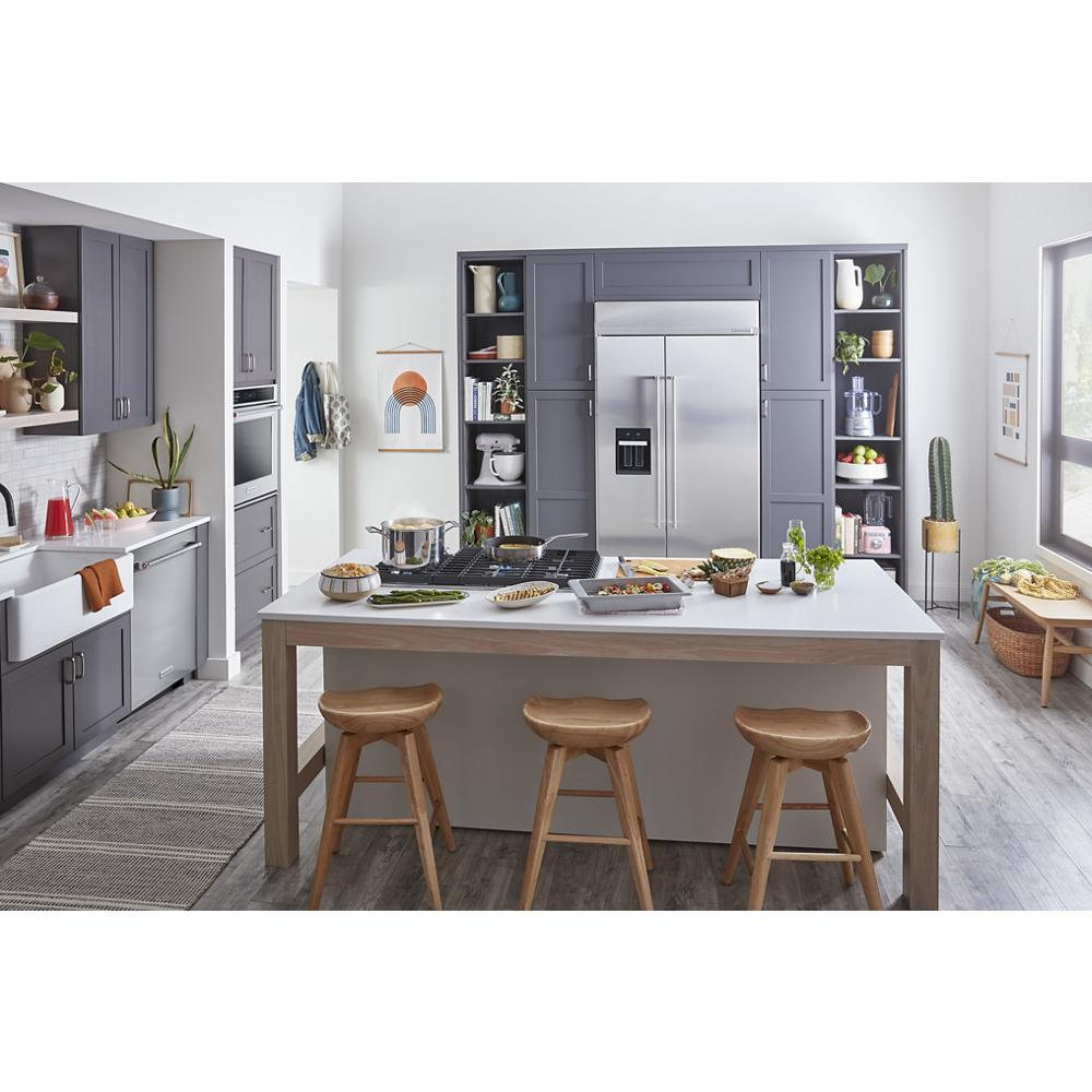 Contemporary kitchen with stainless steel refrigerator, gray cabinets, white island, wooden stools, and modern appliances